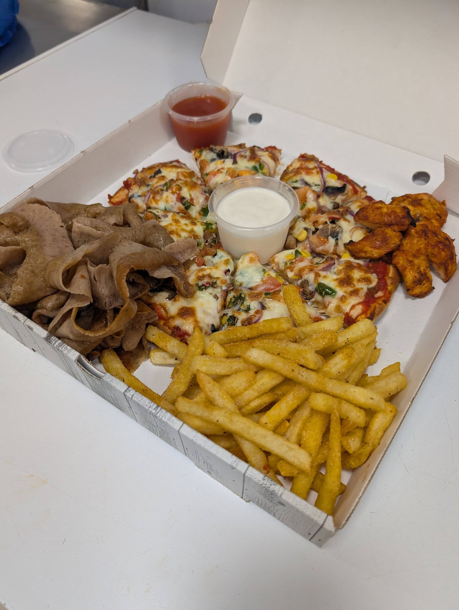 Share box with pizza, doner meat, chicken wings and fries