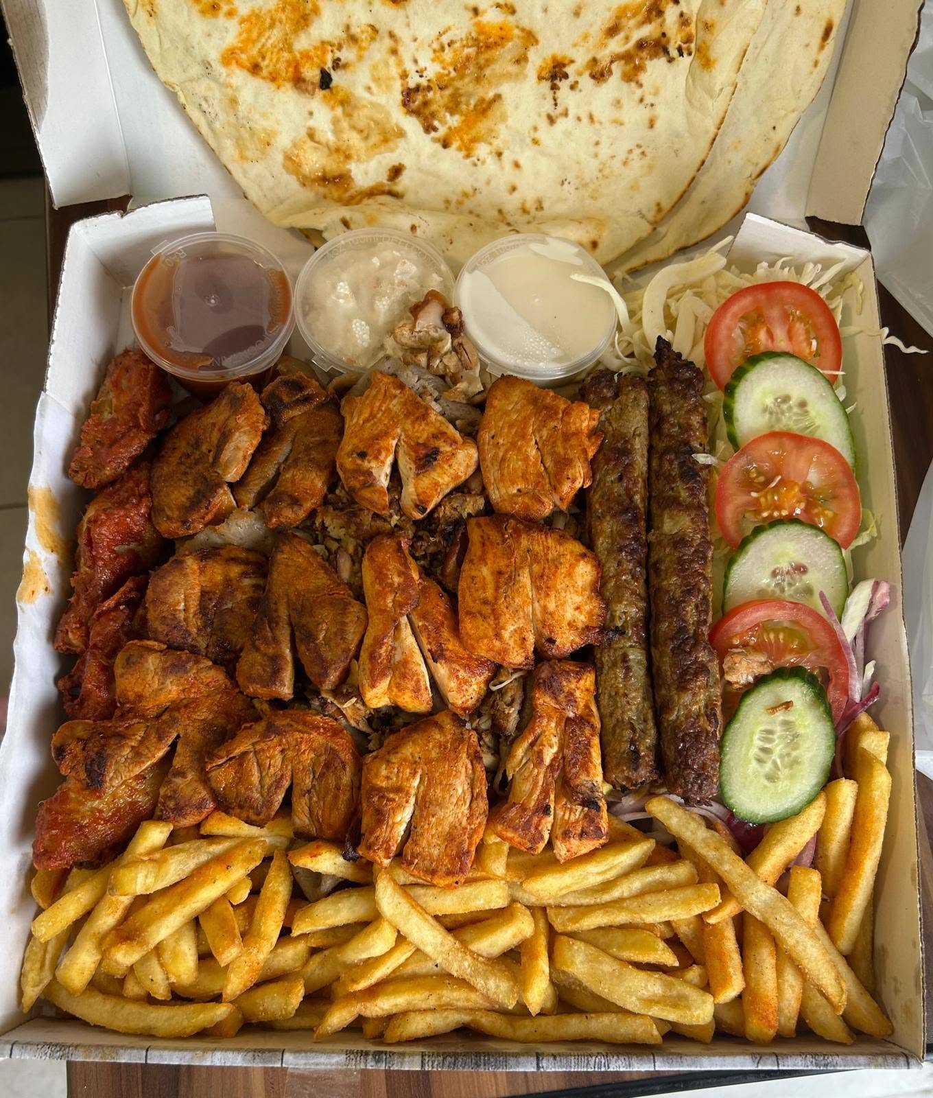 Massive family share box loaded with grilled chicken, kofta skewers, fries and salad